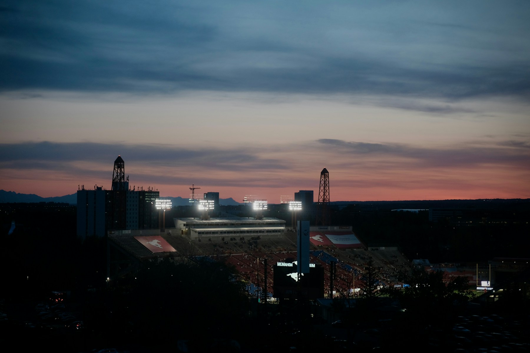 Football stadium glowing at dusk with dramatic lights and American sports atmosphere
